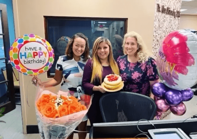 Fairfax Advanced Dentistry team celebrating a birthday with cake, flowers, and balloons